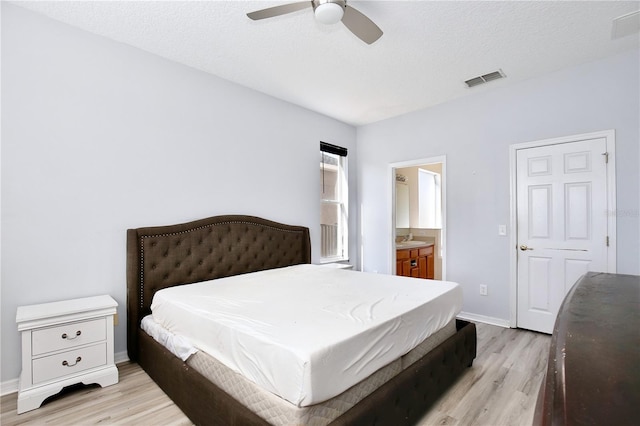 bedroom featuring ensuite bathroom, sink, light hardwood / wood-style flooring, a textured ceiling, and ceiling fan