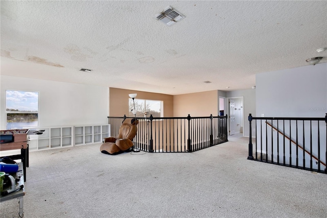 living area with a wealth of natural light, light carpet, and a textured ceiling