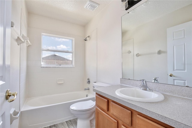 full bathroom with vanity, toilet, tiled shower / bath combo, and a textured ceiling