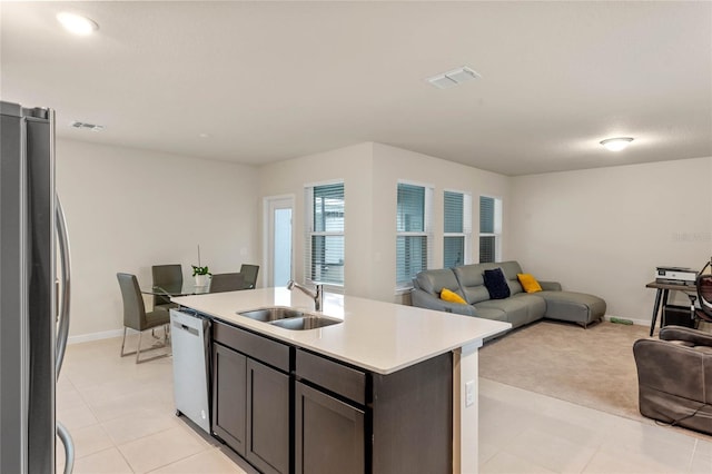 kitchen with a center island with sink, sink, light tile patterned floors, and stainless steel appliances