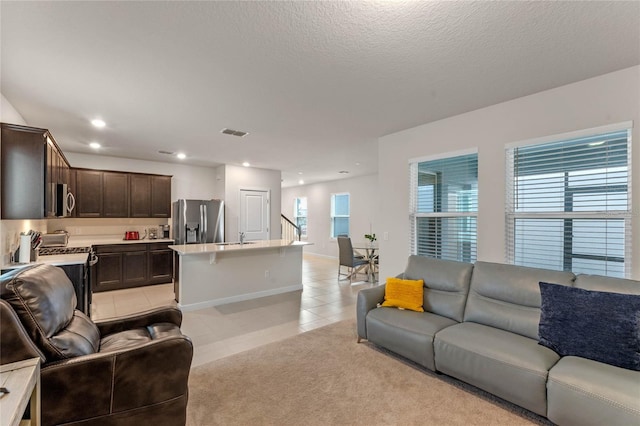 living room with a textured ceiling, light tile patterned floors, and sink