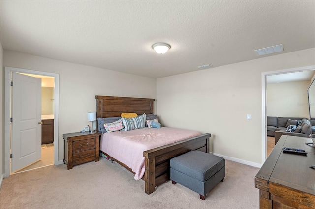 carpeted bedroom with ensuite bathroom and a textured ceiling