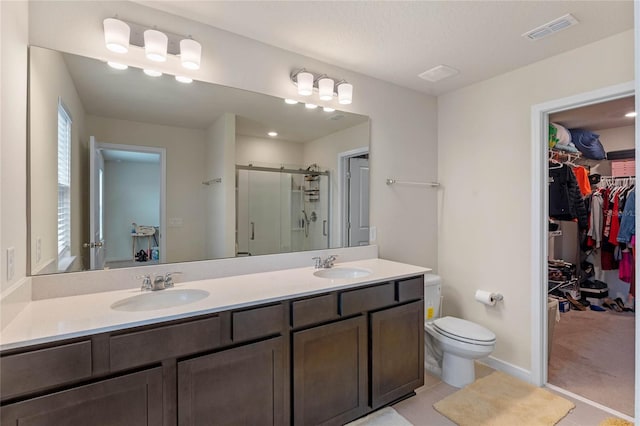 bathroom with tile patterned floors, vanity, toilet, and a shower with shower door