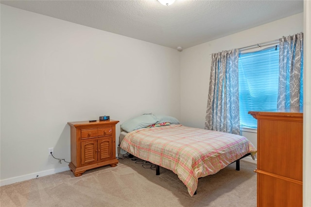 bedroom featuring light colored carpet and a textured ceiling