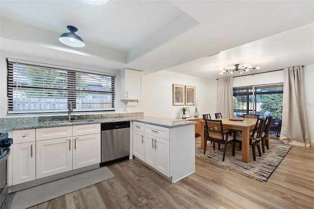 kitchen featuring dishwasher, a raised ceiling, kitchen peninsula, sink, and white cabinetry