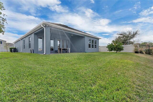 back of house featuring central AC and a lawn