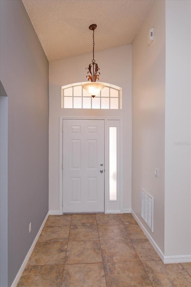 entryway featuring plenty of natural light, high vaulted ceiling, and a textured ceiling