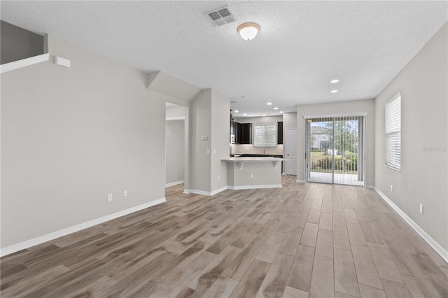 unfurnished living room featuring a textured ceiling and light wood-type flooring