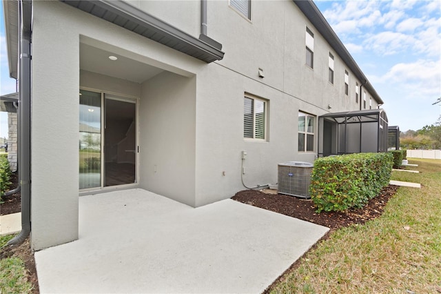 rear view of house featuring glass enclosure, a yard, a patio, and central AC