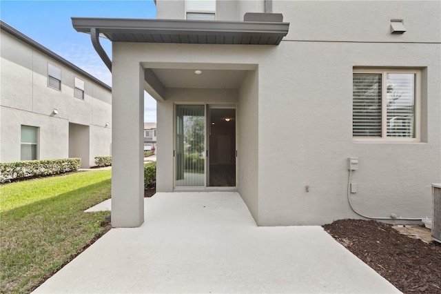 view of exterior entry featuring a patio area and a yard