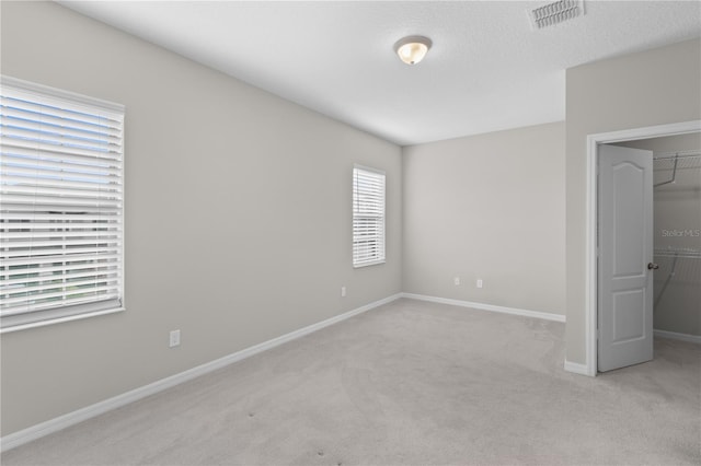 unfurnished bedroom with a spacious closet, light carpet, and a closet