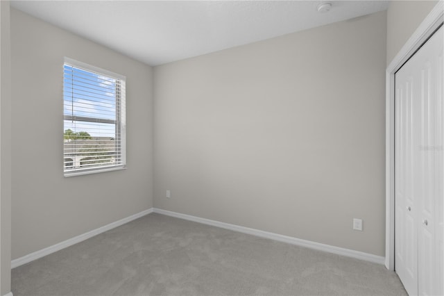 unfurnished bedroom featuring light carpet and a closet