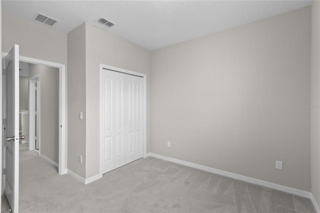 unfurnished bedroom featuring light carpet and a closet