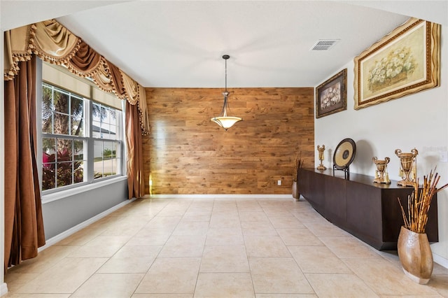 dining area with wood walls and light tile patterned flooring