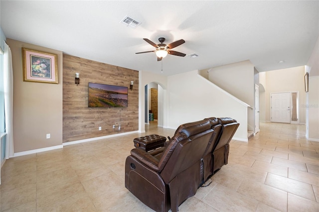 living room featuring ceiling fan, light tile patterned floors, and wooden walls