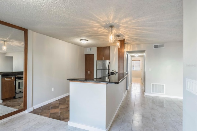 kitchen with sink, stainless steel appliances, pendant lighting, a textured ceiling, and light tile patterned flooring