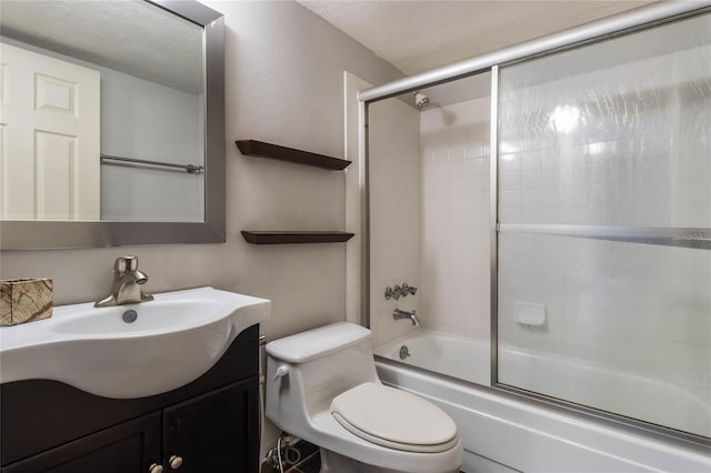 full bathroom featuring a textured ceiling, vanity, toilet, and bath / shower combo with glass door