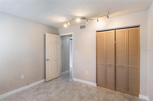 unfurnished bedroom with a textured ceiling, a closet, and light tile patterned flooring