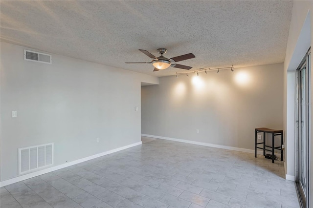 spare room with a textured ceiling, rail lighting, and ceiling fan