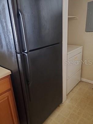 kitchen featuring electric panel, black fridge, and washer / clothes dryer