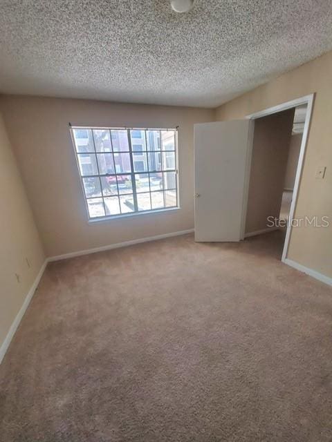 unfurnished room with a textured ceiling and carpet floors