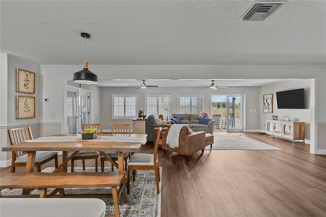 dining area with ceiling fan, french doors, wood-type flooring, and a textured ceiling