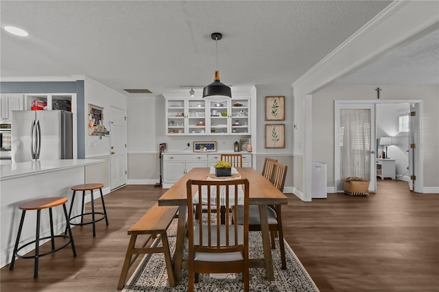 dining space featuring a textured ceiling, dark hardwood / wood-style flooring, and crown molding