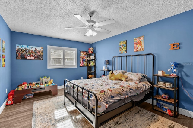 bedroom with hardwood / wood-style floors, ceiling fan, and a textured ceiling