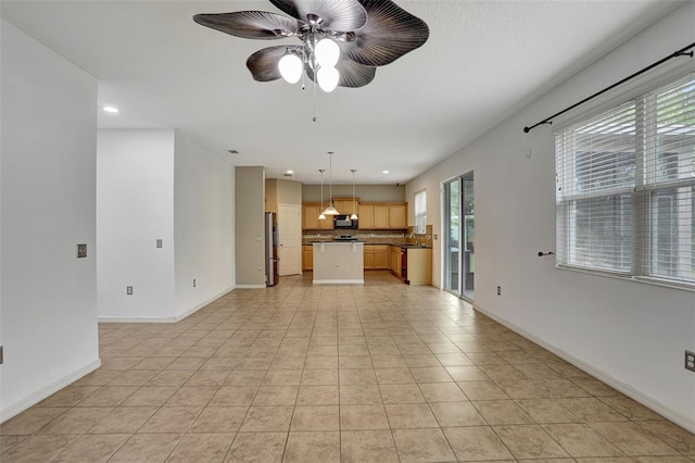 unfurnished living room with ceiling fan, plenty of natural light, light tile patterned floors, and sink