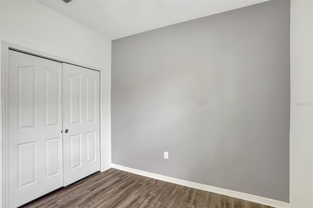 unfurnished bedroom featuring dark hardwood / wood-style flooring and a closet