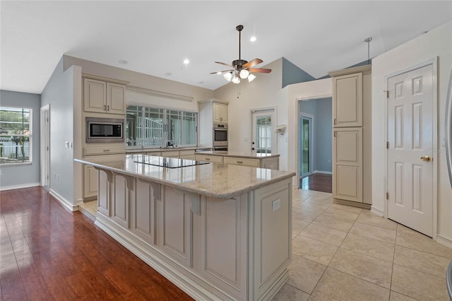 kitchen featuring lofted ceiling, stainless steel appliances, and cream cabinets