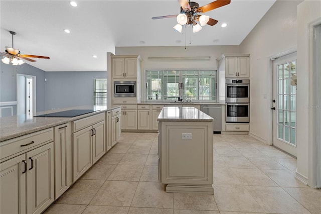 kitchen featuring a healthy amount of sunlight, a kitchen island, cream cabinetry, and appliances with stainless steel finishes