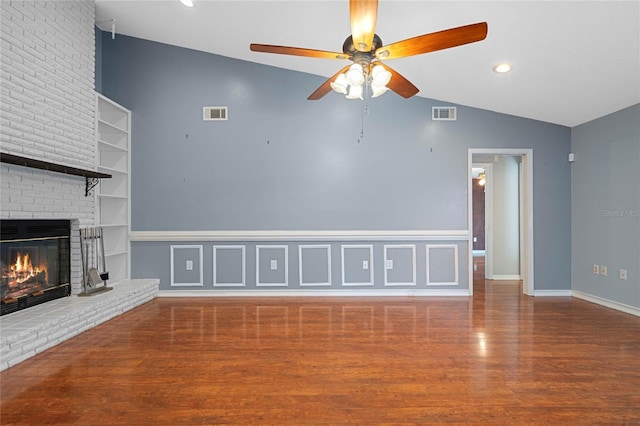 unfurnished living room featuring ceiling fan, a brick fireplace, built in features, hardwood / wood-style floors, and vaulted ceiling