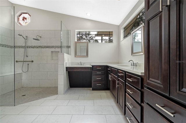 bathroom with tile patterned flooring, a tile shower, vanity, and lofted ceiling