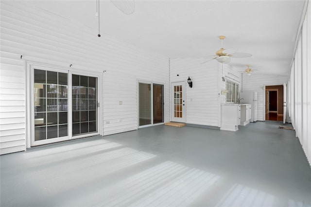 unfurnished living room with a towering ceiling, concrete floors, and ceiling fan