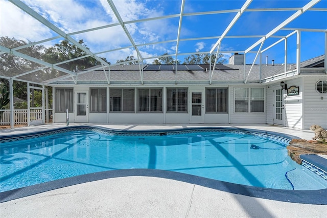 view of swimming pool with a sunroom, glass enclosure, and a patio