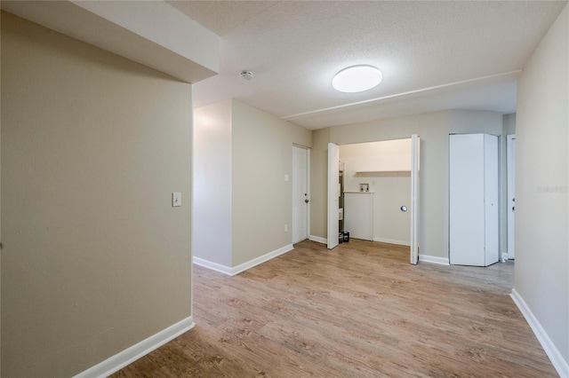 hall with light hardwood / wood-style floors and a textured ceiling