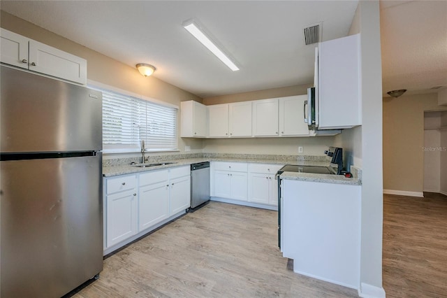 kitchen with white cabinets, appliances with stainless steel finishes, light hardwood / wood-style flooring, and sink