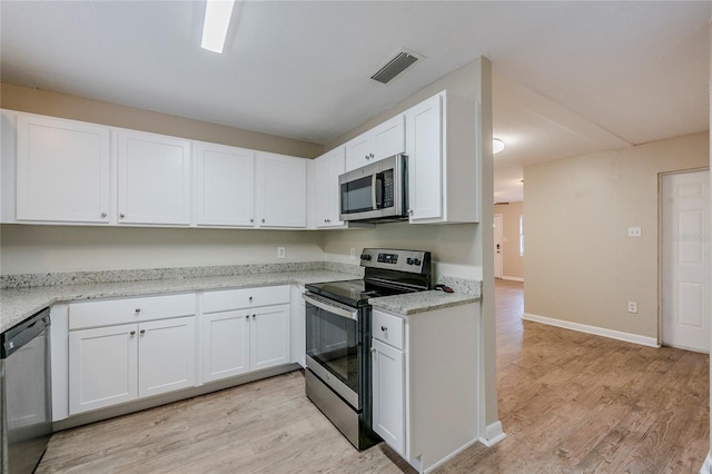 kitchen featuring white cabinets, stainless steel appliances, light wood-type flooring, and light stone counters