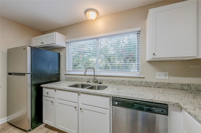 kitchen featuring stainless steel appliances, sink, white cabinets, light hardwood / wood-style flooring, and light stone countertops