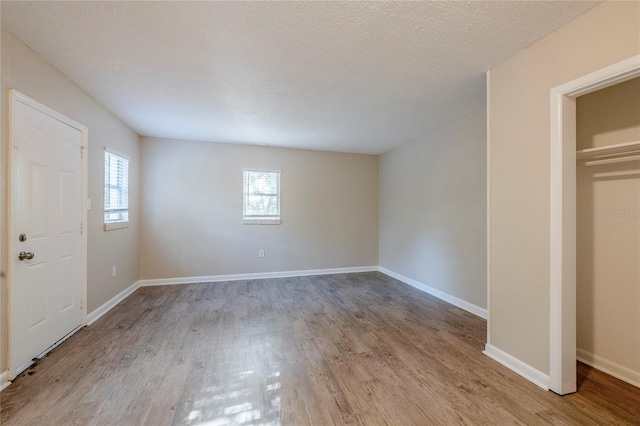 unfurnished bedroom with a textured ceiling, light hardwood / wood-style floors, and multiple windows