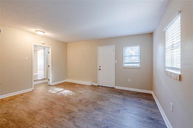 empty room with a textured ceiling and hardwood / wood-style flooring