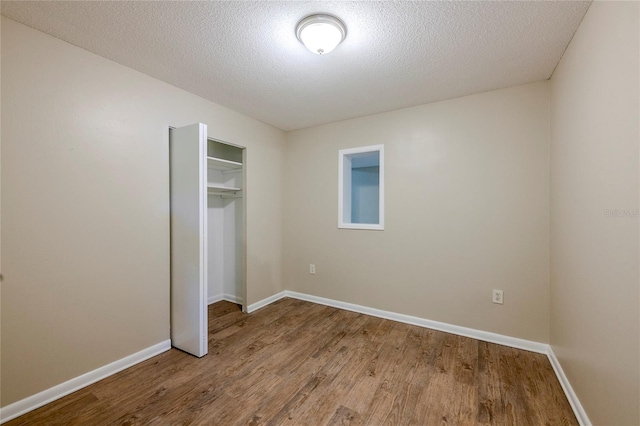 unfurnished bedroom featuring a closet, hardwood / wood-style floors, and a textured ceiling