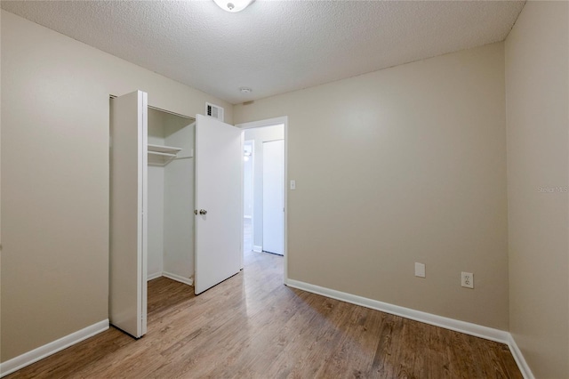 unfurnished bedroom with a textured ceiling, a closet, and light hardwood / wood-style flooring