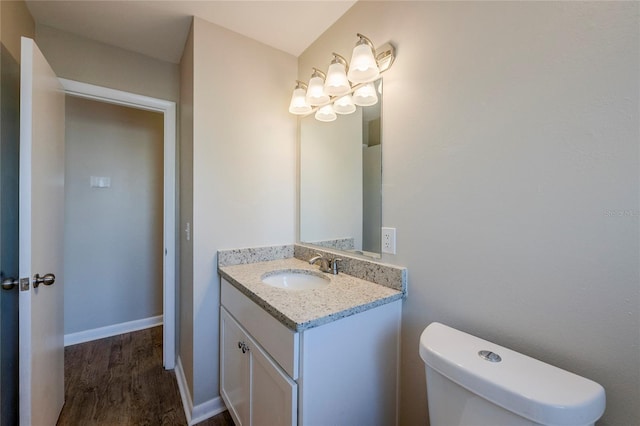 bathroom with toilet, vanity, and hardwood / wood-style floors