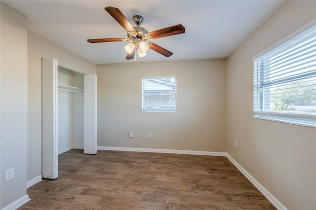 unfurnished bedroom with dark wood-type flooring, ceiling fan, and a closet