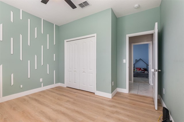 unfurnished bedroom featuring a closet, light hardwood / wood-style flooring, and ceiling fan