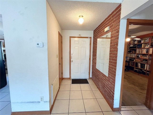 doorway with brick wall, light tile patterned floors, and a textured ceiling