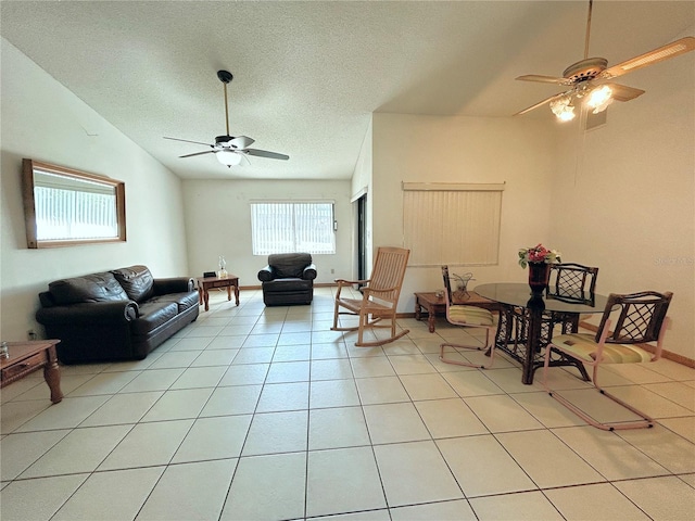 living room featuring lofted ceiling, light tile patterned floors, a textured ceiling, and ceiling fan