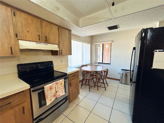 kitchen with stainless steel electric range oven, black refrigerator, light tile patterned floors, and a textured ceiling